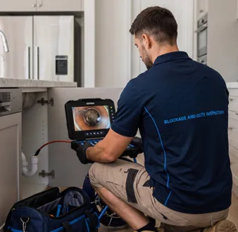Plumber clearing a blocked toilet in a Norwest bathroom